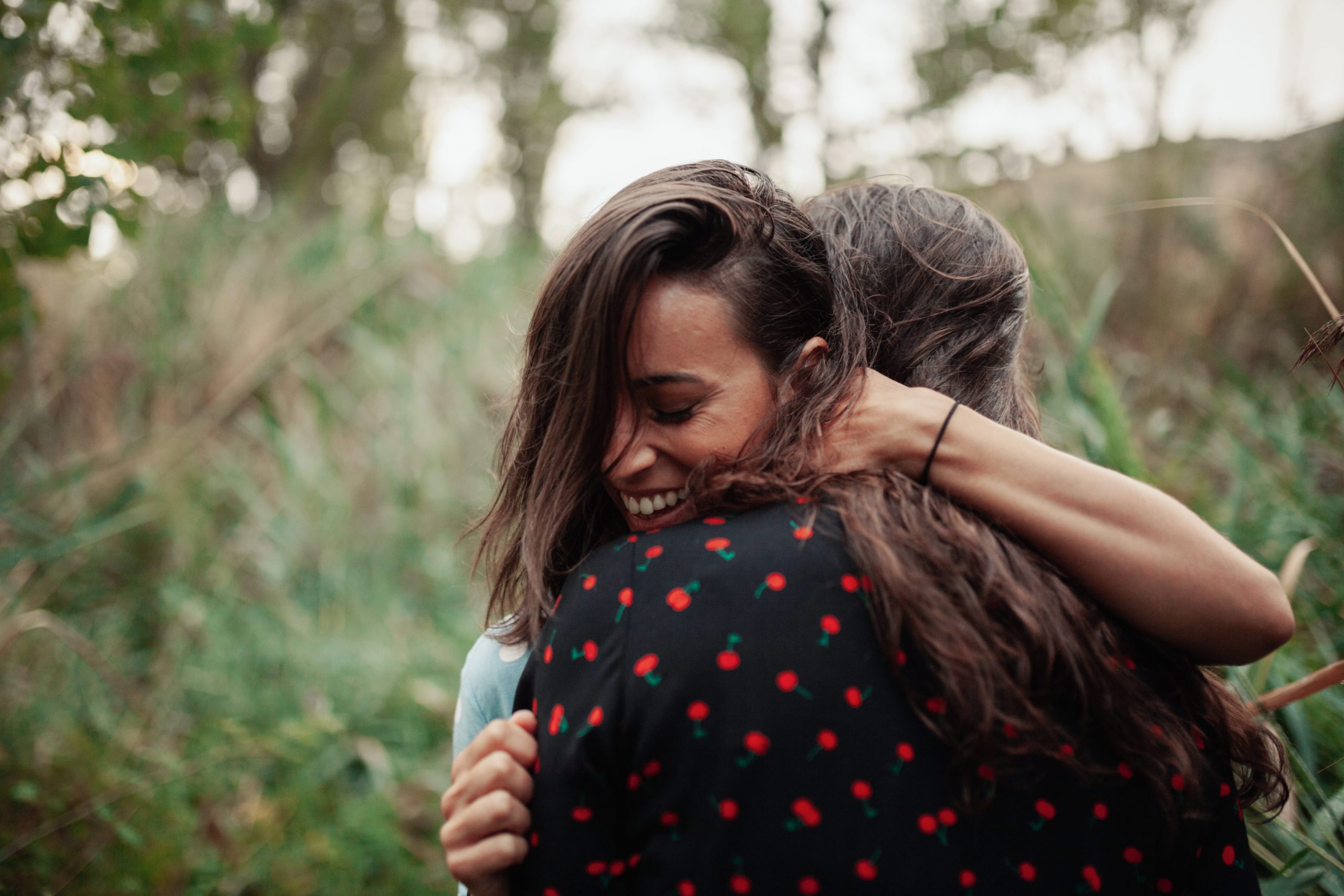 A young woman warmly embraces her friend.