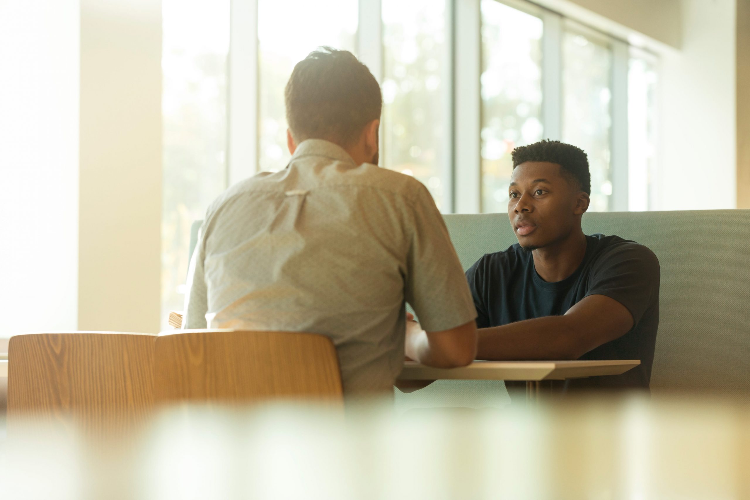 Two men sit across the table from one another having a serious discussion.