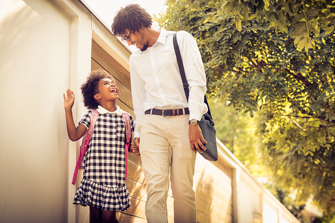 African American daughter and her father walking trough city park and talking.