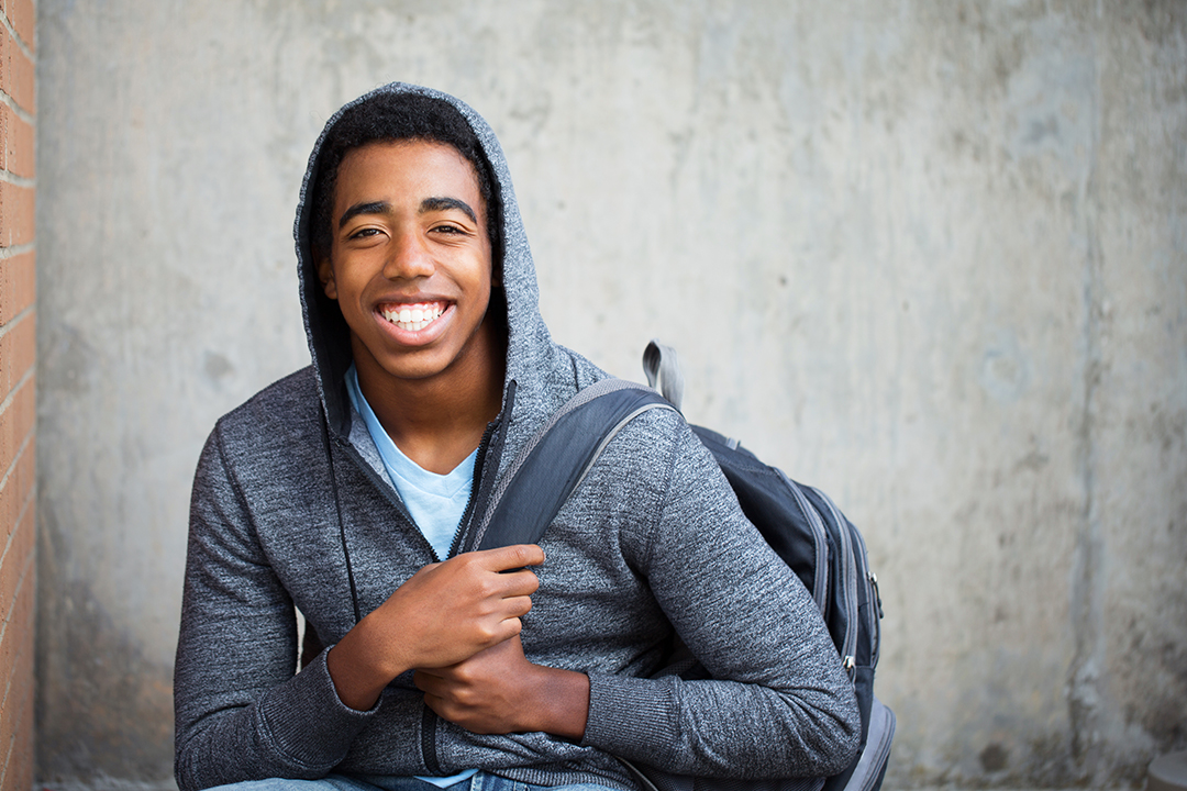 Happy young Black man carrying a backpack