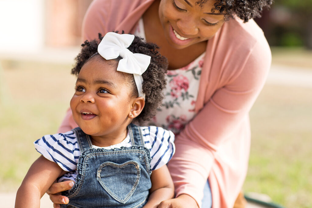 African,American,Mother,Holding,Her,Daughter,Smiling.