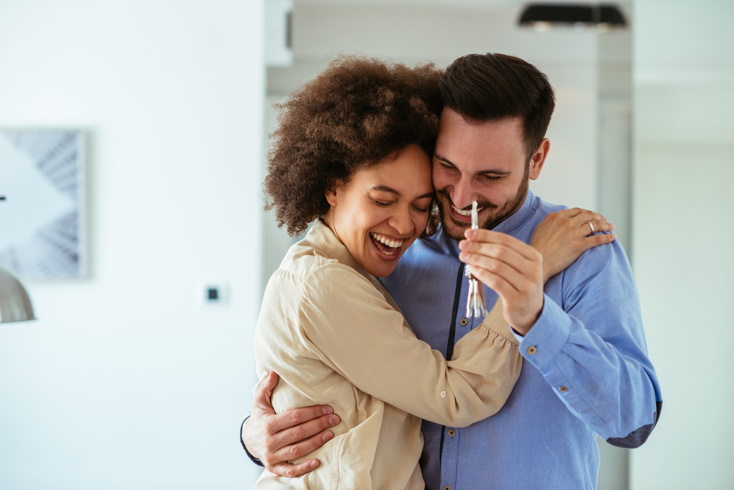 A young couple embraces after receiving a key to their new home.