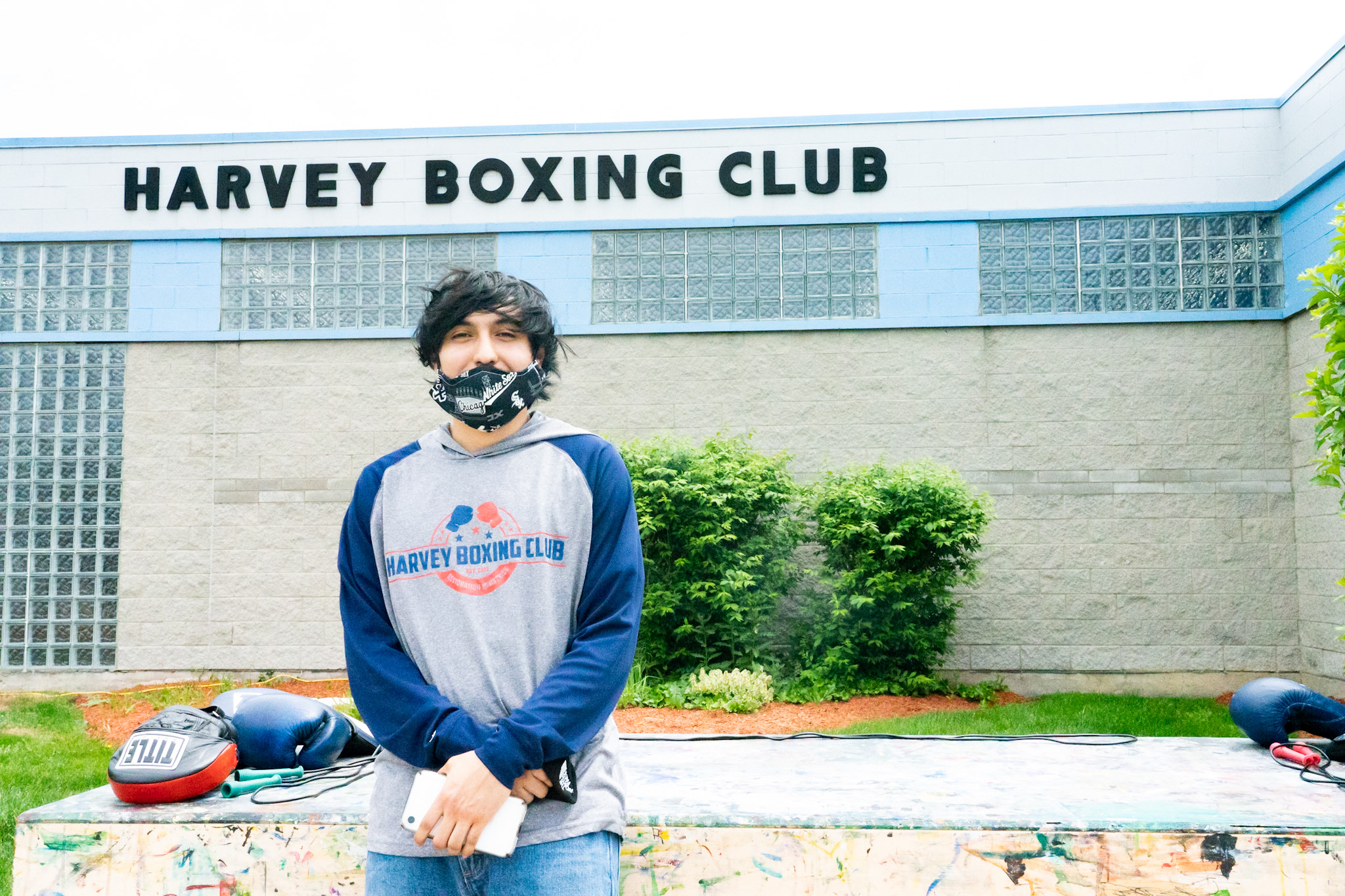 A young man with dark hair stands in front of the Harvey Boxing Club